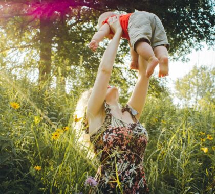 Mom lifting a baby in nature
