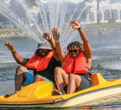 Two men rise their hands as they have fun paddle boating at maumee bay