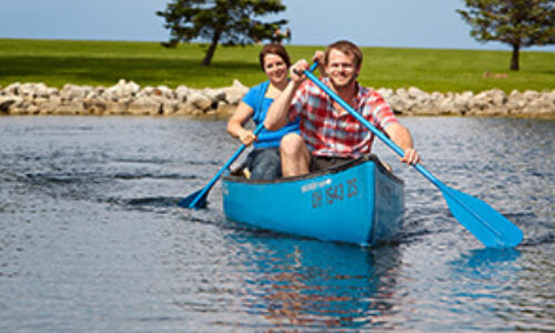 children paddle a blue canoe on maumee bay