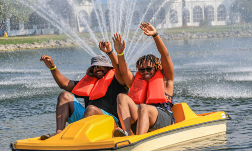 Two men rise their hands as they have fun paddle boating at maumee bay
