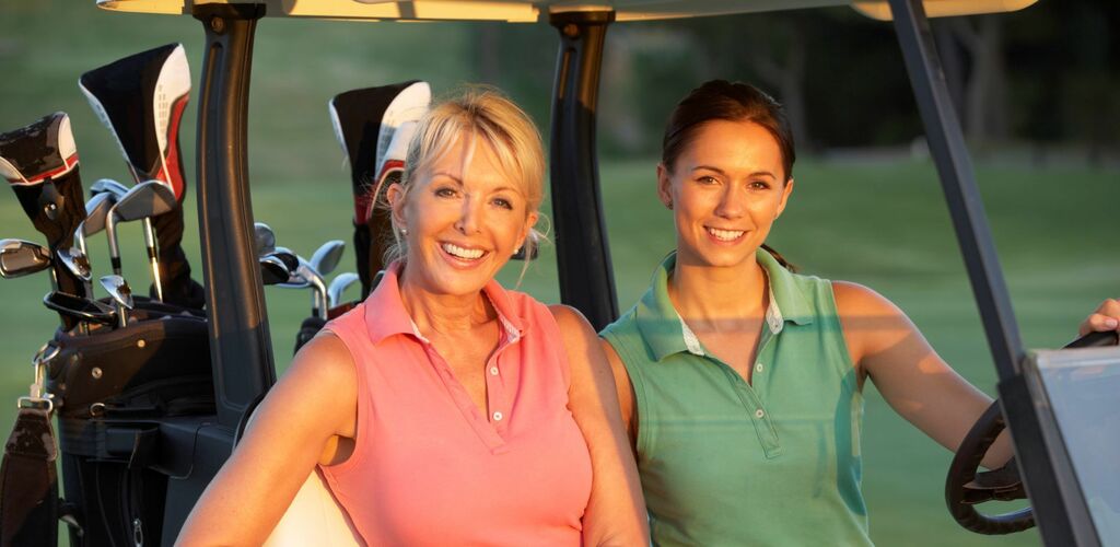 Ladies golfing, sitting on a golf cart
